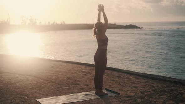 Silhouette of Woman Doing Yoga Exercises at Early Morning in Ray of Sun