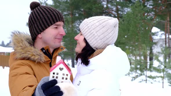 Man and woman in love outdoor date in winter with symbol of home and love