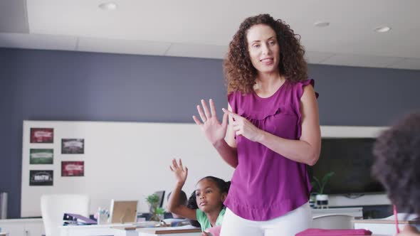 Video of caucasian female school teacher and diverse school children studying in classroom