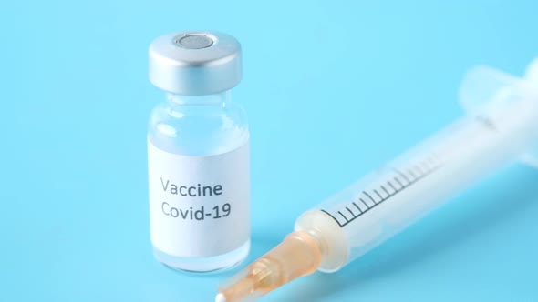 Close Up of Coronavirus Vaccine and Syringe on Blue Background