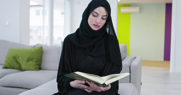 Woman Reading Quran on the Sofa Before Iftar Dinner During a Ramadan Feast at Home