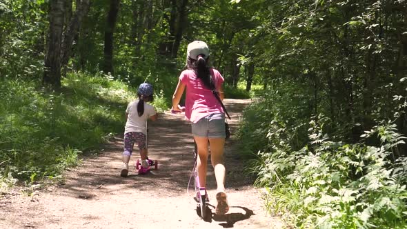 Two Little Asian Girls Riding Scooters in the Park Day