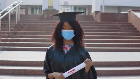 Young African American Female Graduate in Protective Medical Mask Standing in Front of the Camera