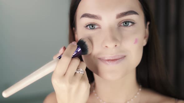 Beautiful Young Charming Caucasian Woman Applying Blush to Her Cheeks