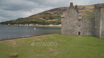 toric British palace of Hamilton dynasty. Green grass valley and mountain at sea coast of Loch-Ranza, Arran Island, Scotland, United Kingdom, Europe
