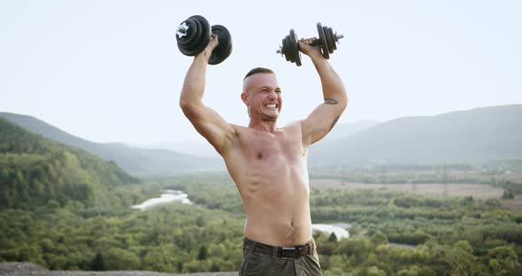 Front View of Handsome Purposeful Strong Young Athlete with Naked Torso Which Doing Power Exercises