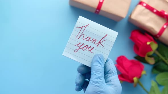 Person Hand in Protective Gloves Holding Thank You Letter