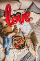 Young couple having breakfast in bed and holding sign love - PhotoDune Item for Sale