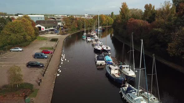 Descending aerial shot onto canal with geese, swans & sail boats