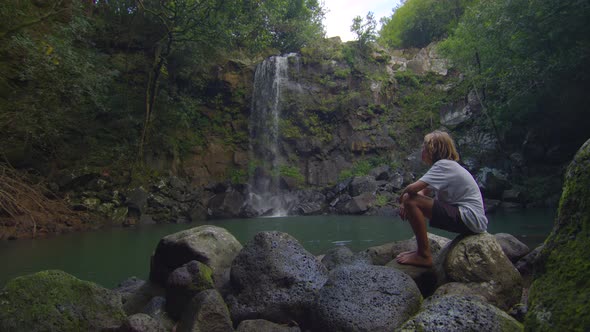 Teenager on the Shore of a High Wild Beautiful Waterfall