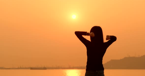 Woman raising hand up under sunset 