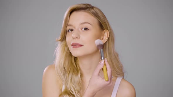 Young Woman with Brush Applying Makeup