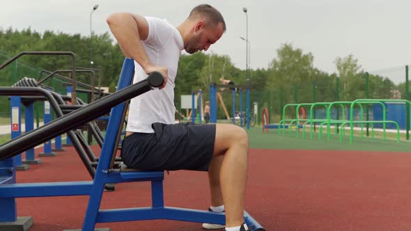 Man Trains in the Air on a Simulator Does Triceps Exercises