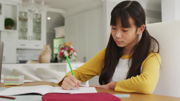 Asian father using smartphone and laptop working in kitchen with son and daughter doing schoolwork