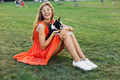 young happy smiling woman in orange dress having fun playing with dog in park - PhotoDune Item for Sale