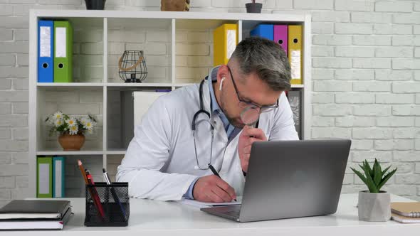 Doctor in hospital office writes diagnosis in notebook looks magnifying glass