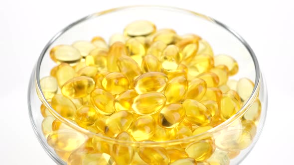 Capsule of Omega 3 in clear bowl rotation on white background. Omega 3 gold fish oil capsule