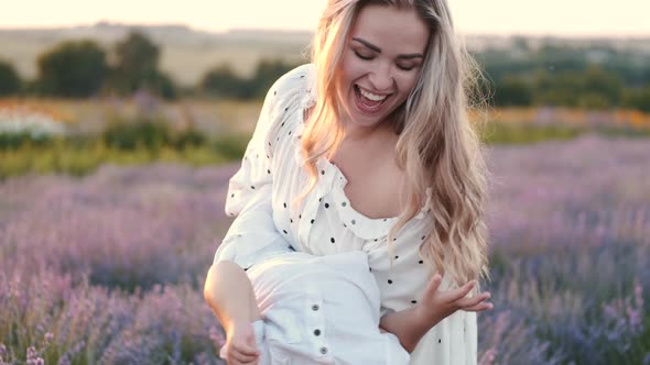 Pretty Mother with Her Kid in a Lavender Field on Sunset