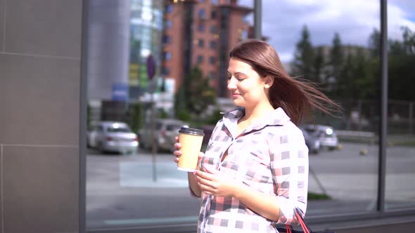 Young Girl Goes After Shopping with Bags in Her Hands Drinking Coffee