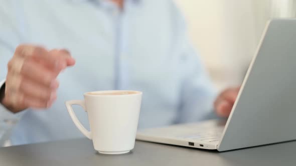 African Man Working on Laptop and Drinking Coffee Close Up