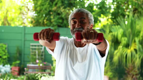 Senior man exercising with dumbbell at home