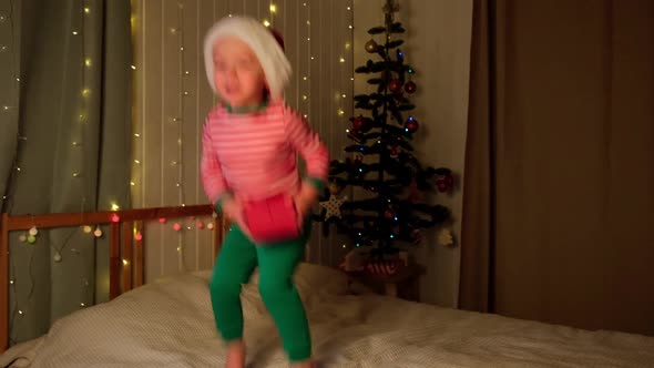 Christmas Boy Jumping in Santa Hat at Home Evening