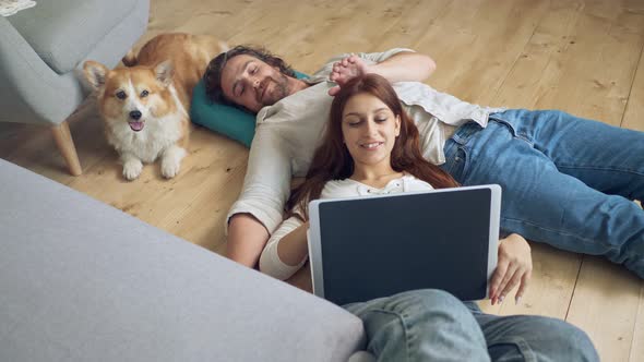 A Lovely Couple Lying on the Floor Using a Laptop, Spouses Enjoying of Each Other.