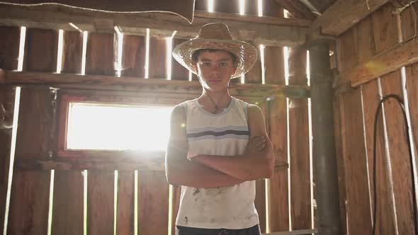 Adolescent Boy in Straw Hat in the Farmers Country Barn Viewed From Low Angle Standing with and