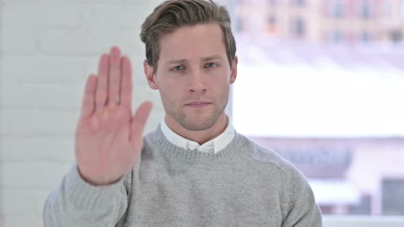 Portrait of Creative Young Man Doing Stop Sign with Hand 