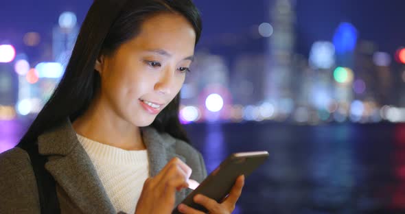 Business woman using cellphone in Hong Kong city at night