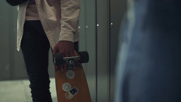 Boy Hand Holding Skateboard with Stickers in School Hall Close Up