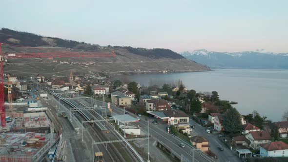 Drone flying past construction crane, revealing small Swiss town