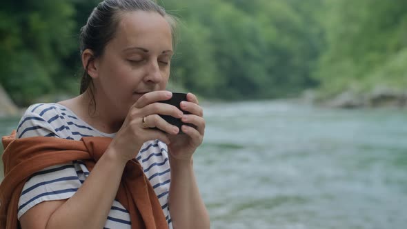 Closeup Woman drinks mocha coffee and looking at mountain river, road trip and staycation concept