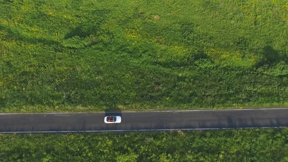 Aerial Shot of White Convertible Car Riding Through Empty Rural Road. Four Young Unrecognizable