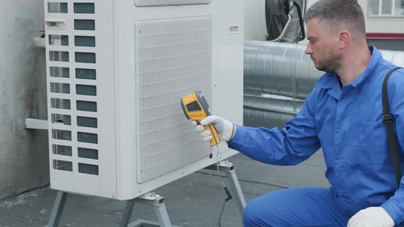 Technician uses a thermal imaging infrared thermometer to check the condensing