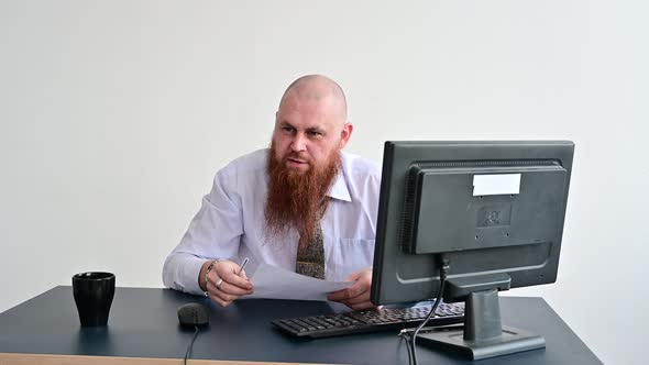 Portrait of a Bald Man at a Desk Looking at a Report and Cursing