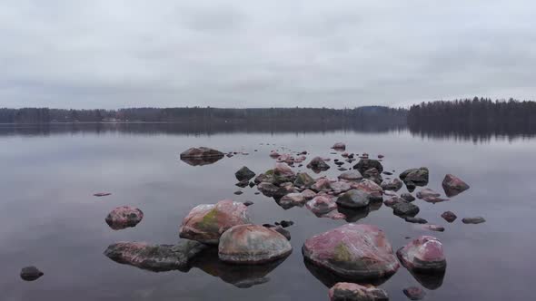 Island of Stones Scattered in Water on Finland Lake Aerial Approach