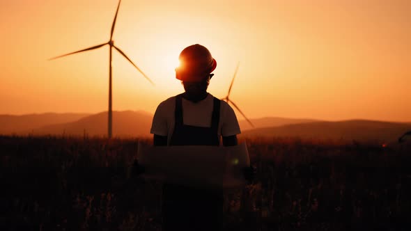 Silhouette African American Man with Blueprints in Hands Standing Among Farm