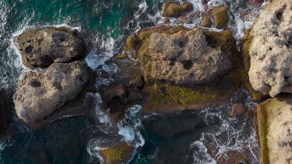 Aerial View. Rocky Coast and Azure Sea. Waves Crash Against Large Rocks