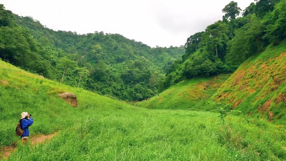 Young Asian female traveler is enjoying the beautiful scenery of the mountains and the green fields.