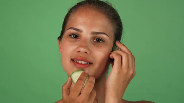 Gorgeous Woman Massaging Her Face with Slices of Cucumber