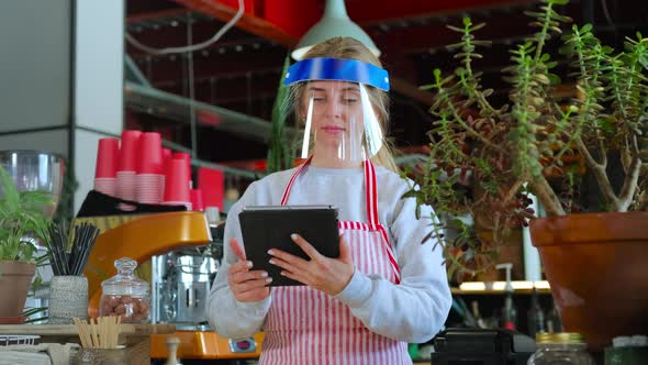 Female Barista in Face Shield Using Tablet PC