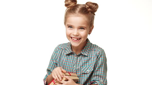 Young Cute Caucasian Girl Kid with Two Hair Buns and Plaid Shirt Opening Small Box with Gift and