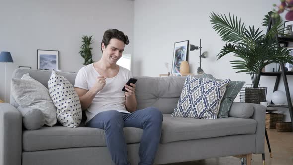 Excited Man Celebrating Success, while Using Smartphone
