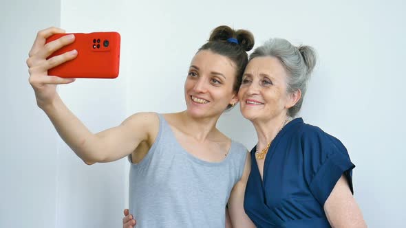 Adult Daughter and Senior Mum are Taking Selfportrait Picture Selfie on Red Smartphone Together