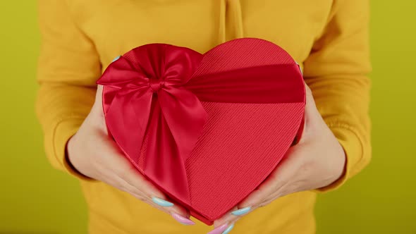 Body Part of Woman with Red Gift Box in Form of Heart on Yellow Background