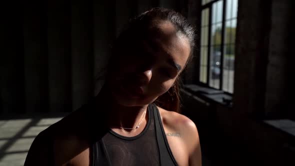 Sporty Woman Is Relaxing During Training in Gym, Closeup Portrait in Bright Sunshine