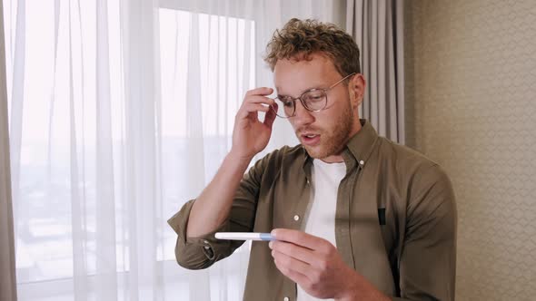 Frustrated Young Man Look at Pregnancy Test at Home