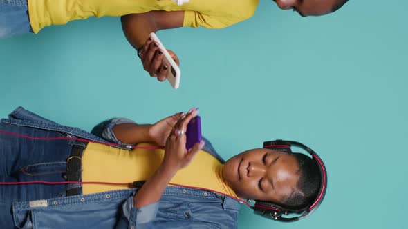 Vertical Video Couple Wearing Headphones and Listening to Music with Mobile Phone