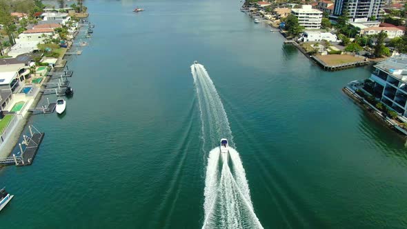 Two speedboats racing along a canal in the shadows  of luxurious  Surfers Paradise apartments and Lu